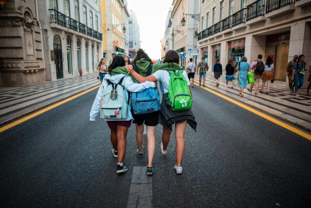 pexels-photo-20136323-20136323 Three young friends walk arm-in-arm on a Lisbon street, showcasing friendship and travel spirit.